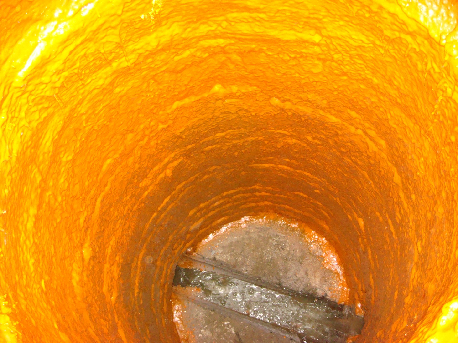 Spray-applied coating lining the inside of a below-grade concrete structure with no seams or joints