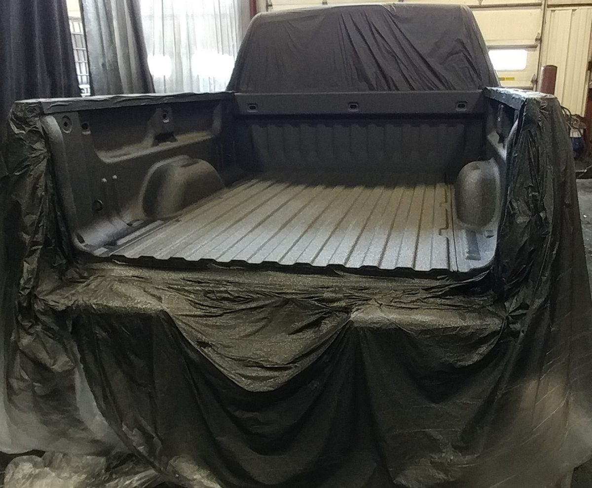 Flak Jacket bed liner being spray-applied to a masked truck bed