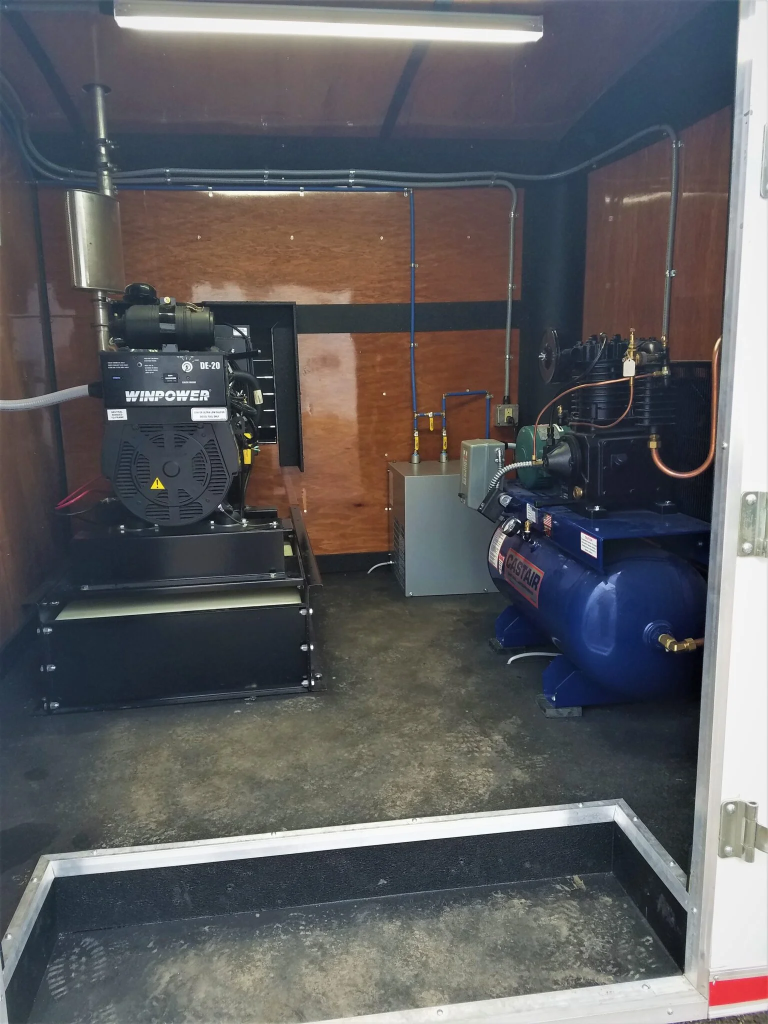 Custom enclosed trailer spray foam rig — finished wood-paneled interior build by Oak Ridge