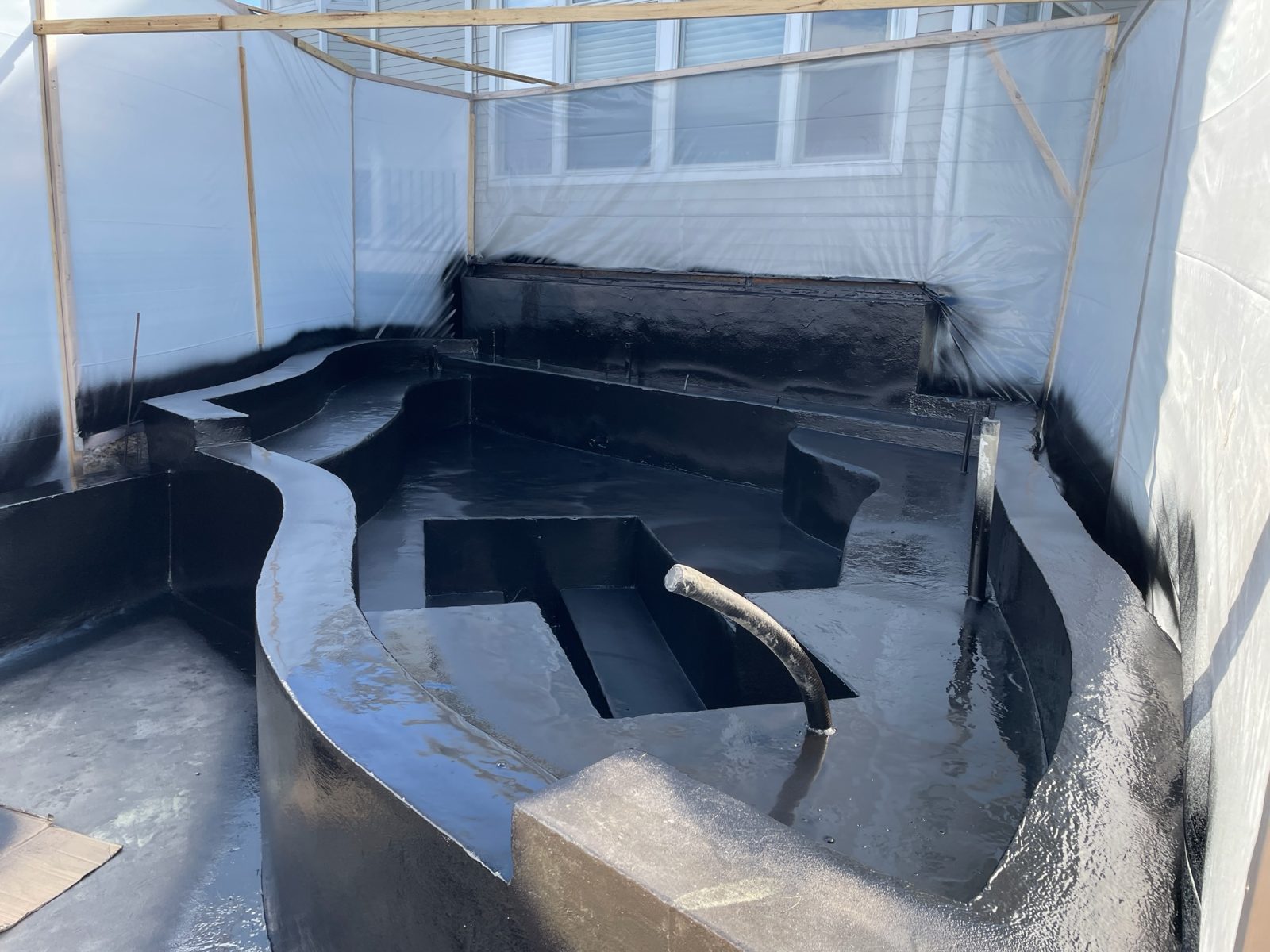 Spray-applied black polyurea liner in a custom pond before filling
